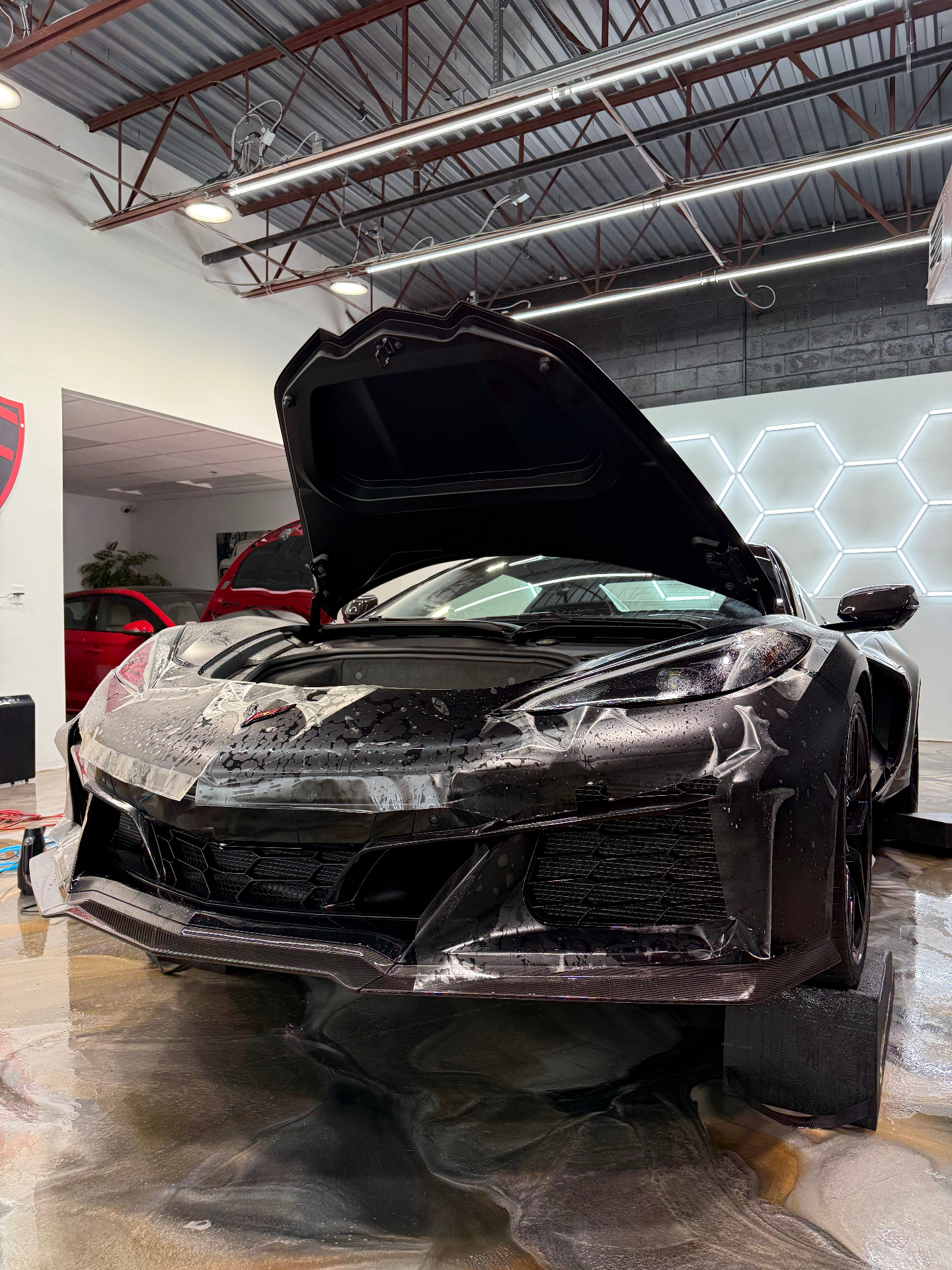 Black Corvette receiving paint protection film installation inside Colorado Customs shop