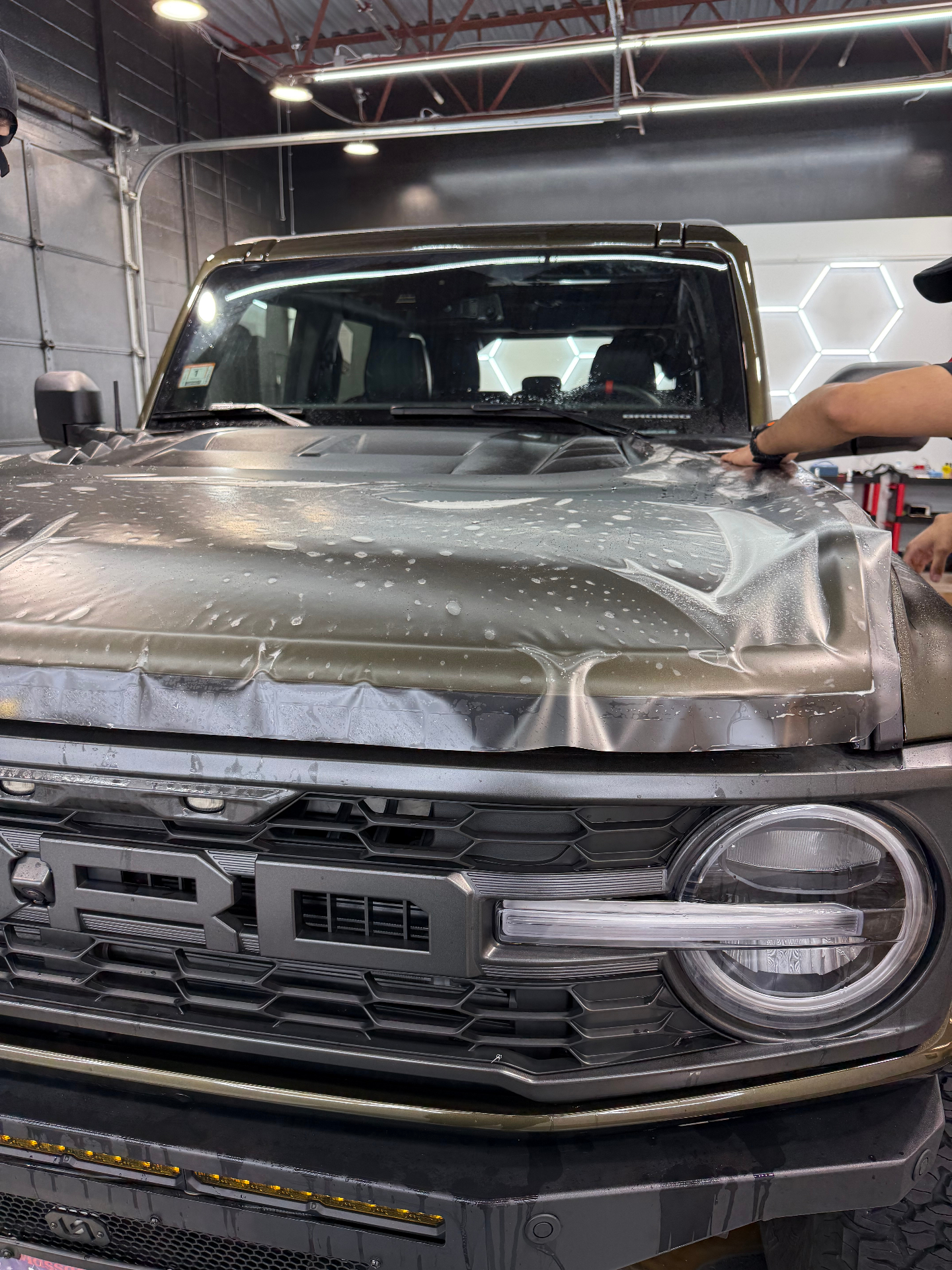 Bronco hood being wrapped with clear paint protection film at Colorado Customs